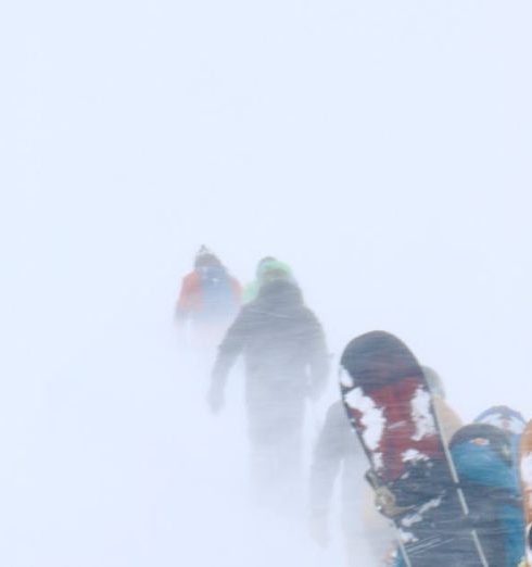 Snowshoeing Gear - Snowboarders Walking in Snowstorm