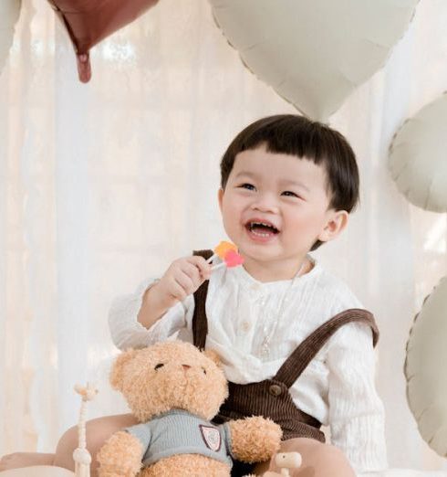 Baby Shower Gifts - Laughing Boy Sitting with a Teddy Bear at his Birthday Party