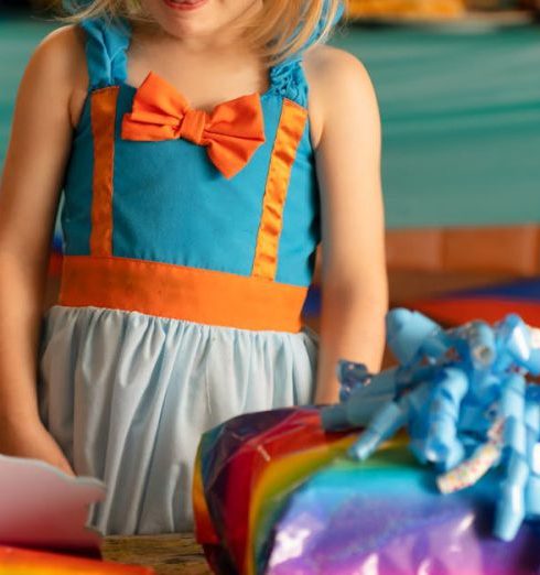 Teacher Gifts - A Girl in Blue and Orange Dress Standing Beside the Wooden Table