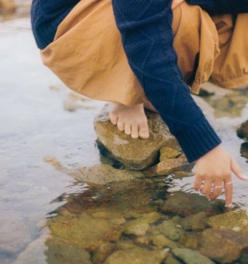 Kids' Clothing - Child Squatting and Playing in Water