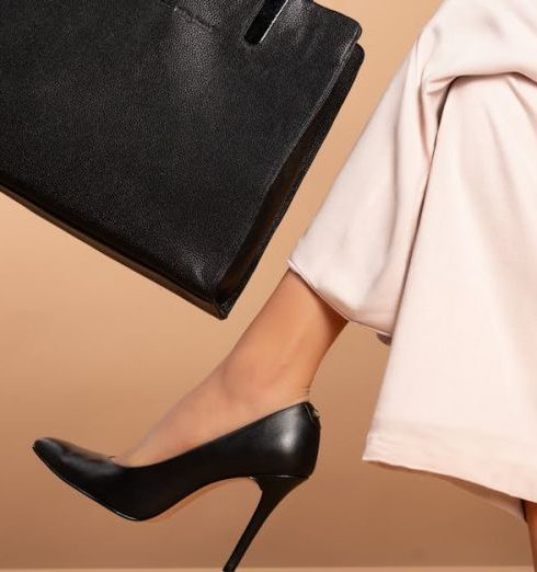 Designer Boutiques - A Woman Wearing Black Heels and Holding a Bag