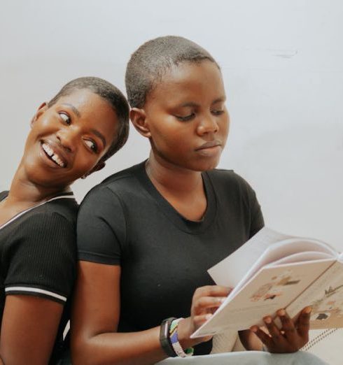 Book Clubs - Women Sitting on the Rattan Sofa while Reading a Book