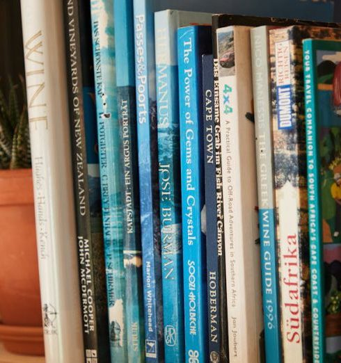 Travel Books - Wooden shelf filled with different interesting books near pots with green plants at home