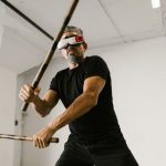 Fitness Gadgets - Man using an Arnis while wearing Virtual Reality Glasses