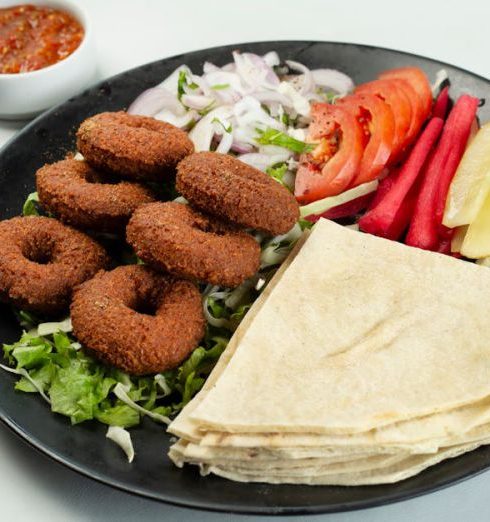 International Foods - Onion Rings with Vegetables and Bread on Black Plate