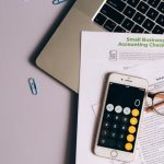 Budget Gadgets - A Mobile Phone and Eyeglasses on Top of the Documents Near the Laptop