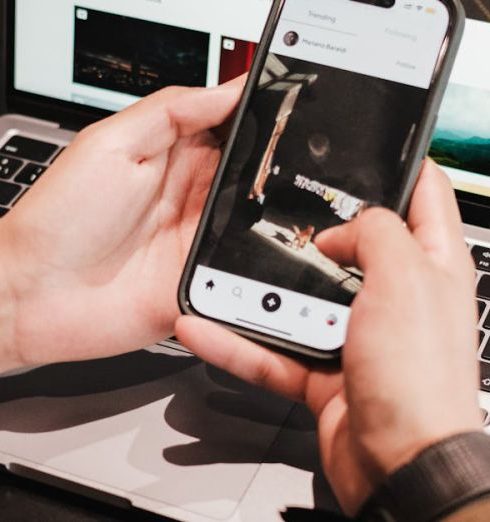 Productivity Gadgets - Hands Holding Smartphone over Laptop