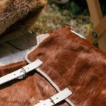 Clothing Fairs - Real Fur Jacket and Cap Lying on a Wooden Bench next to a Table with Clay Dishes