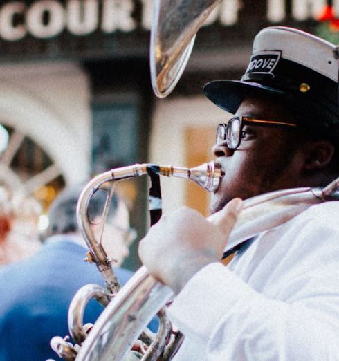 Live Entertainment - Man in White Shirt and a Cap Playing the Tuba on a Street