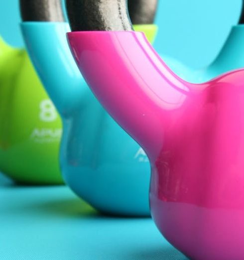 Fitness Equipment - Green, Blue, and Pink Kettle Bells on Blue Surface