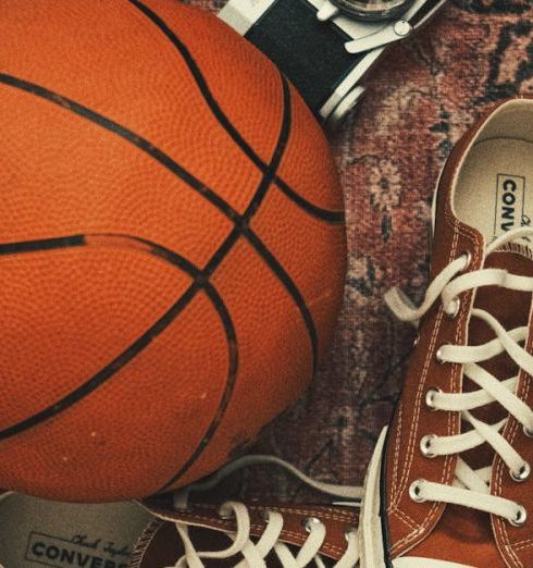 Sports Apparel - Sneakers, a Basketball and an Analog Camera Lying on an Old Rug