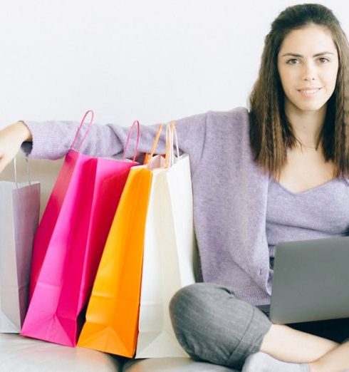 Sales And Discounts - A Woman Sitting on a Couch with Paper Bags