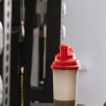 Sports Nutrition - A Bottle with a Protein Shake Standing on a Machine at the Gym