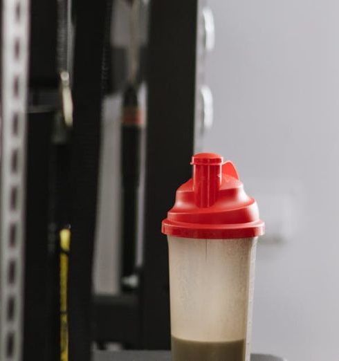 Sports Nutrition - A Bottle with a Protein Shake Standing on a Machine at the Gym