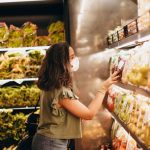 Supermarkets - Woman Browsing through Groceries on a Shelf in a Supermarket