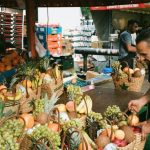 Grocery Stores - Man Fixing Basket of Fruits on Table