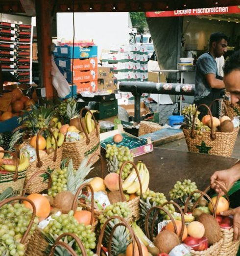 Grocery Stores - Man Fixing Basket of Fruits on Table