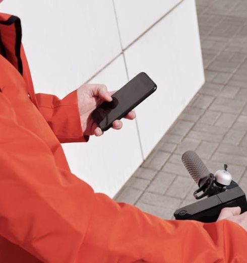 Delivery Apps - Man in Orange Jacket Holding Black Smartphone