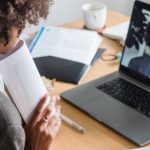 Remote Team - A woman engaged in a virtual meeting at her desk, surrounded by documents and a laptop.