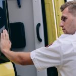 Response Time - Emergency medical technician securing ambulance door, focusing on readiness.