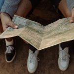 Journey Mapping - Close-up of a group exploring a map, planning a travel adventure while sitting outdoors.