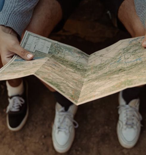 Journey Mapping - Close-up of a group exploring a map, planning a travel adventure while sitting outdoors.