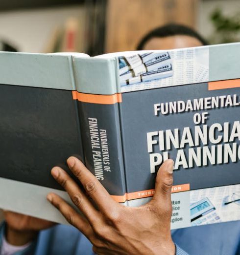 Knowledge Base - A professional individual in a suit reading 'Fundamentals of Financial Planning' indoors.