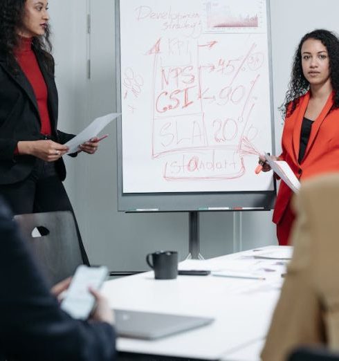 Performance Metrics - Two women leading a business meeting with a focus on KPI strategies and performance metrics.