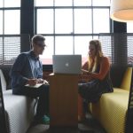 Feedback - Two adults discussing work and collaborating in a modern office lounge area.