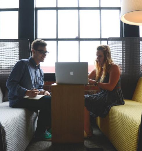 Feedback - Two adults discussing work and collaborating in a modern office lounge area.