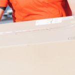 Free Shipping - African American delivery man holding a cardboard box in a residential area, smiling.