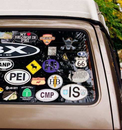 Personalization - A vintage van adorned with various travel stickers parked on an autumn street with colorful foliage.