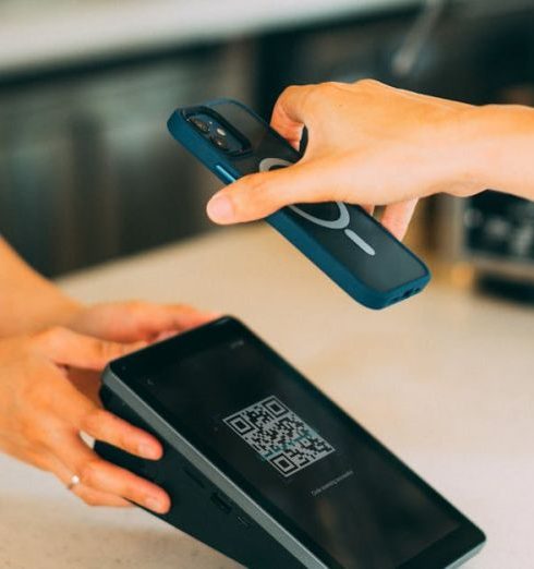 Checkout - Close-up of a contactless payment using a smartphone and QR code scanner in a modern retail setting.