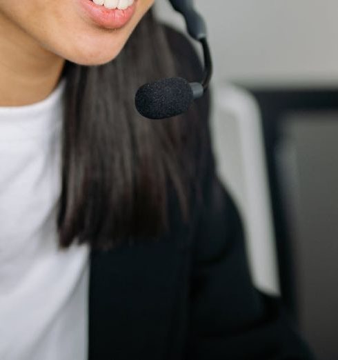 Live Chat - Asian woman in a black blazer using a headset for customer service in an office setting.