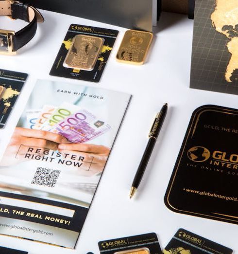 Order Value - Flat lay of promotional materials for gold investment, featuring brochures, cards, and gold bars.