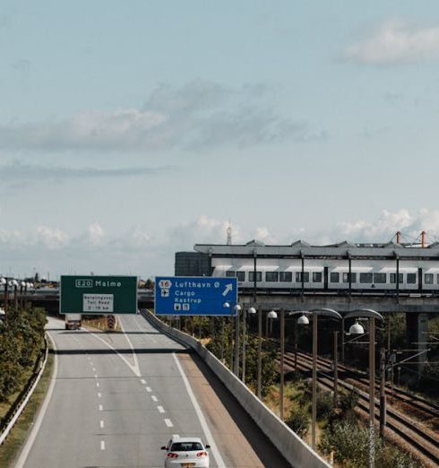 Cross-Border - Aerial view of a highway leading to Sweden from Copenhagen with visible road signs and a train track.