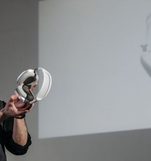 Product Launches - A bearded man presenting a pair of wireless headphones during a business meeting.