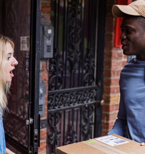 Delivery Services - A woman is surprised as she receives a delivery package from a courier at her doorstep.