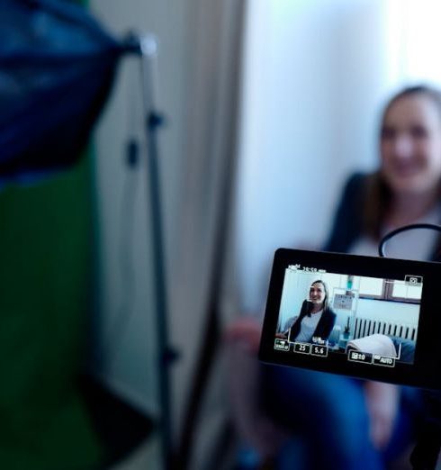 Video Marketing - Woman being recorded in a professional studio setup, using video camera and lighting equipment.