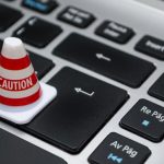 Data Security - Miniature caution cone on a computer keyboard symbolizing data security and control.