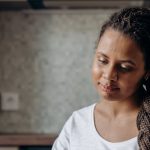 Customer Journey - Woman with dreadlocks shopping online using a laptop in her kitchen.