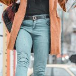 Social Proof - Fashionable woman walking on street with coffee and newspaper on a winter day.