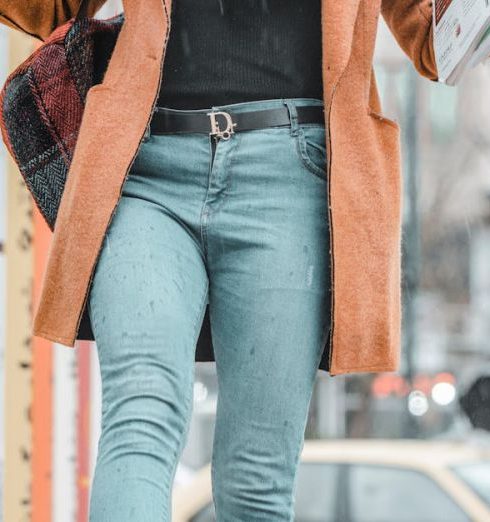 Social Proof - Fashionable woman walking on street with coffee and newspaper on a winter day.