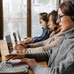 CRM - Professional customer service team working in a modern office setting with headsets and laptops.