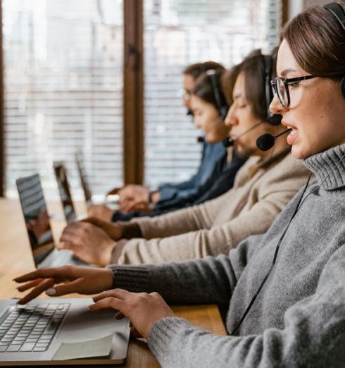 CRM - Professional customer service team working in a modern office setting with headsets and laptops.