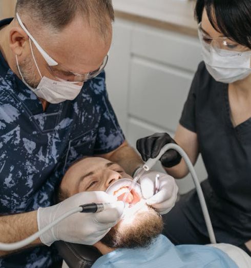 Follow-Up - Dentist and assistant conducting a dental exam with protective gear.