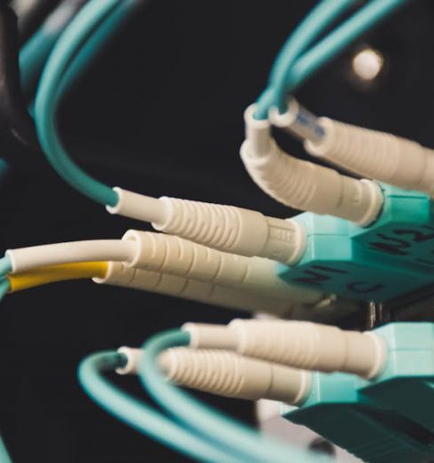 Networking - Detailed view of fiber optic cables and ports in a server room, showcasing connectivity.