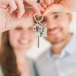 Closing - Young couple holding keys to their new home, symbolizing a fresh start and investment in real estate.