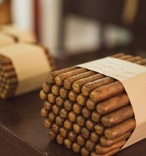 Product Bundles - Stacks of cigar bundles wrapped in paper, placed on a wooden surface inside a manufacturing facility.