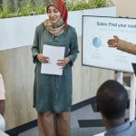 Sales Team - Team of professionals discussing sales strategy during a business presentation in a modern office.